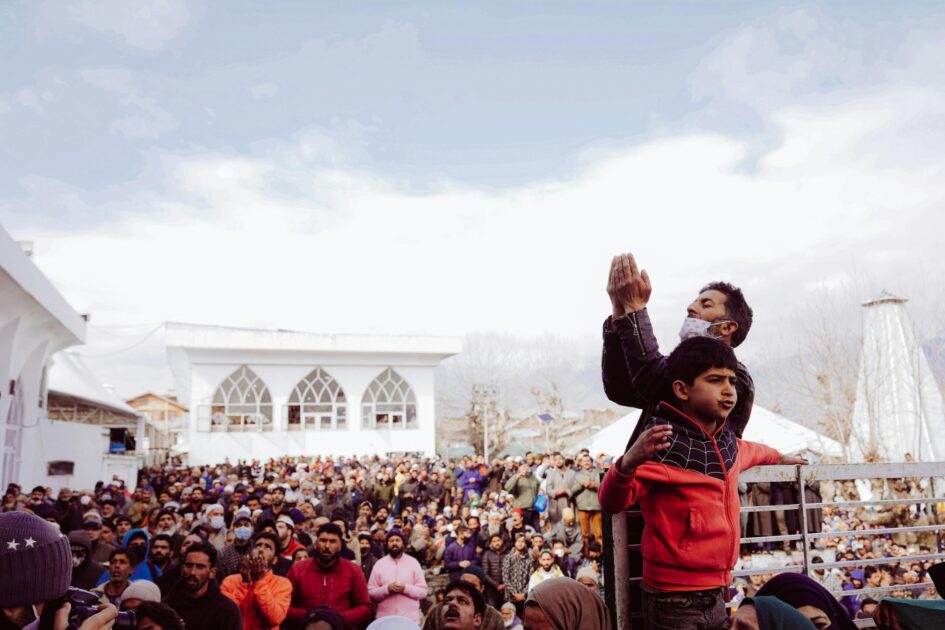A large crowd gathers for a religious event on a cloudy day, showcasing cultural unity.