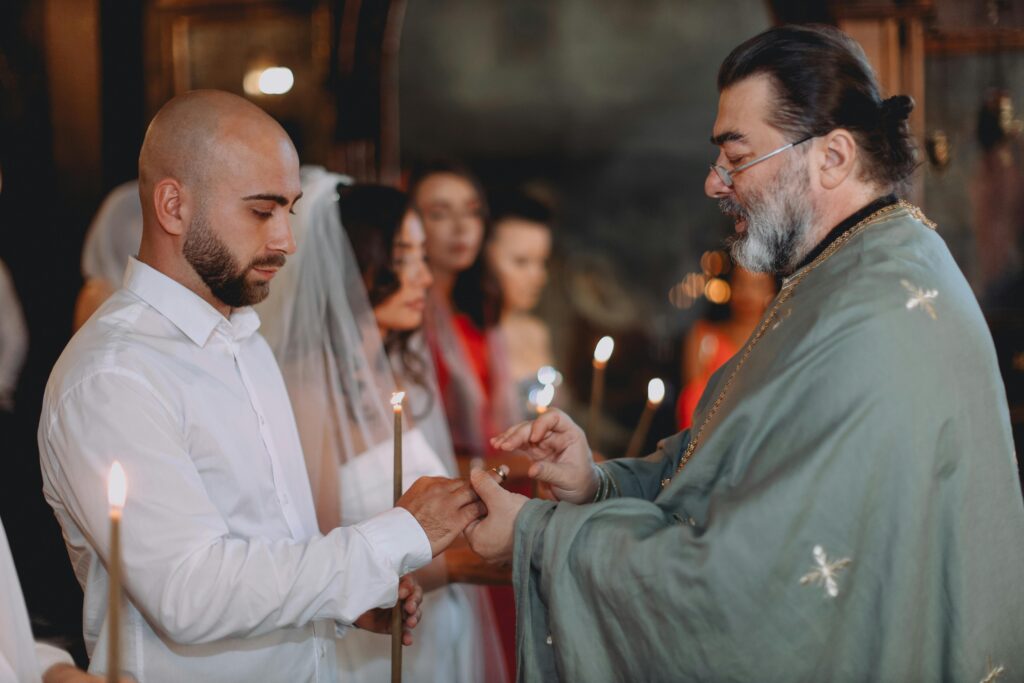 Intimate moment of a wedding ceremony led by orthodox priest in a church setting.