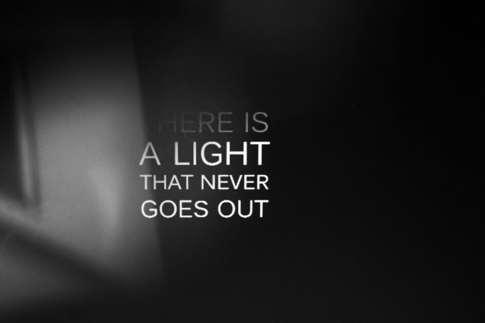 Inspirational quote 'There is a light that never goes out' on a black gradient background.