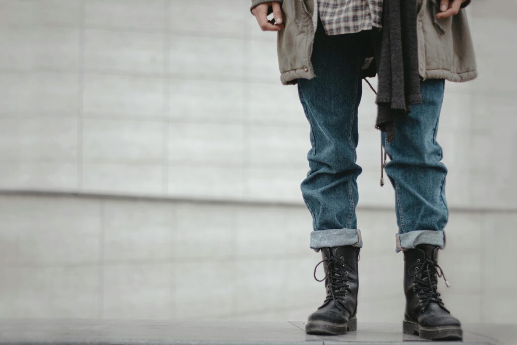 Trendy outfit featuring rolled denim jeans and black leather boots in a casual urban setting.