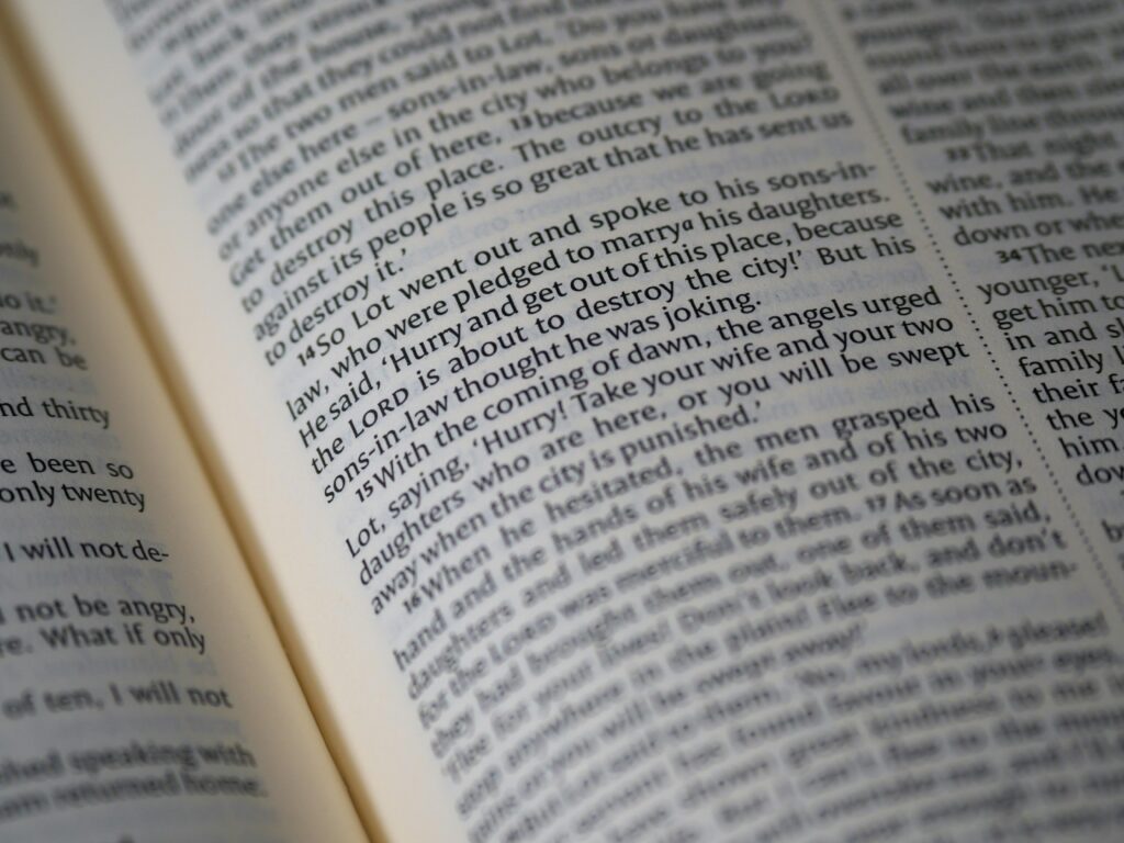 A detailed close-up of a Bible page showing scripture text and verses.