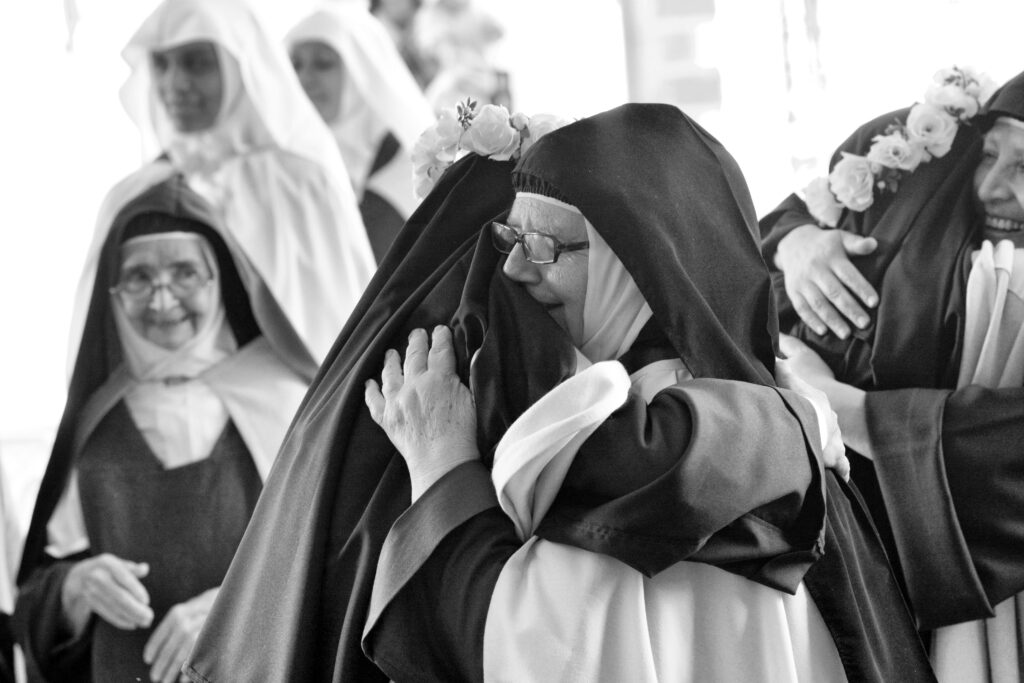 A heartfelt embrace between nuns at a religious celebration, capturing joy and camaraderie.