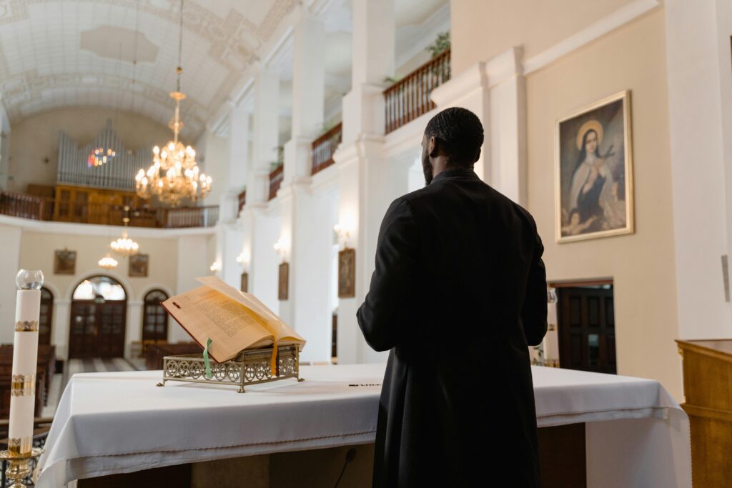 A priest in a traditional church setting, standing near the altar during a religious ceremony.
