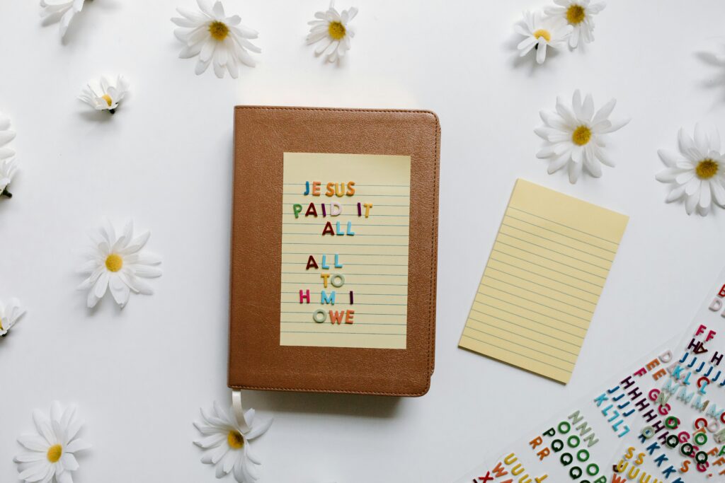 Colorful religious quote on a Bible surrounded by daisies offering peaceful inspiration.