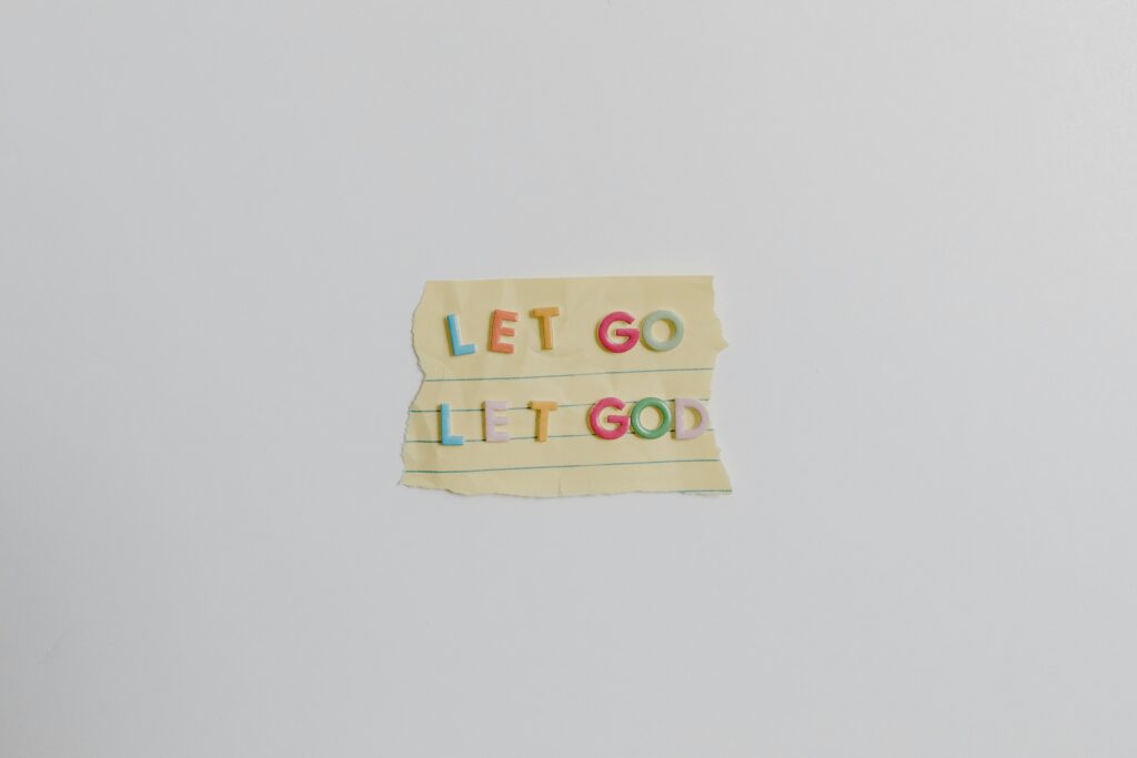 Minimalist image of a torn paper with the phrase 'Let Go, Let God' in colorful letters.