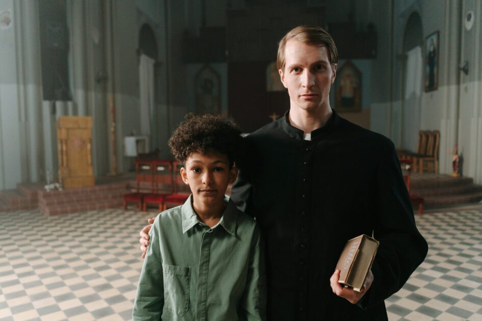 A priest and a boy standing inside a church, symbolizing faith and mentorship.